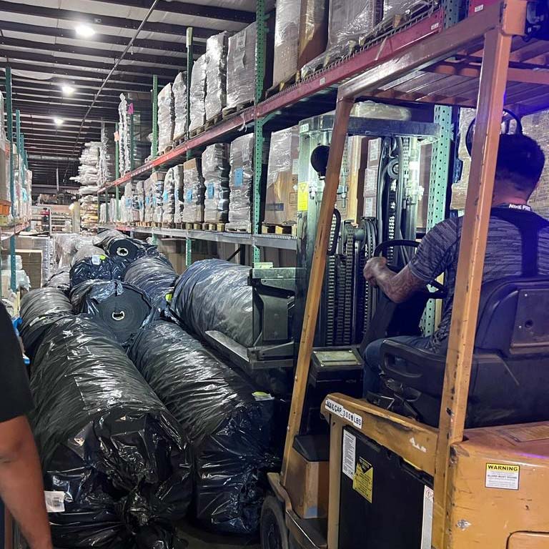forklift in aisle of materials in factory warehouse